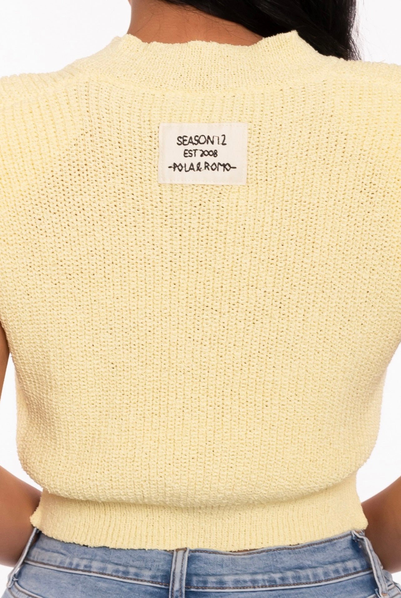 Close-up of a woman wearing a yellow knit top.