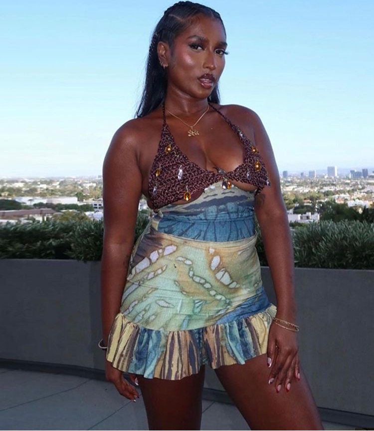 Woman wearing a patterned top and skirt with a cityscape in the background