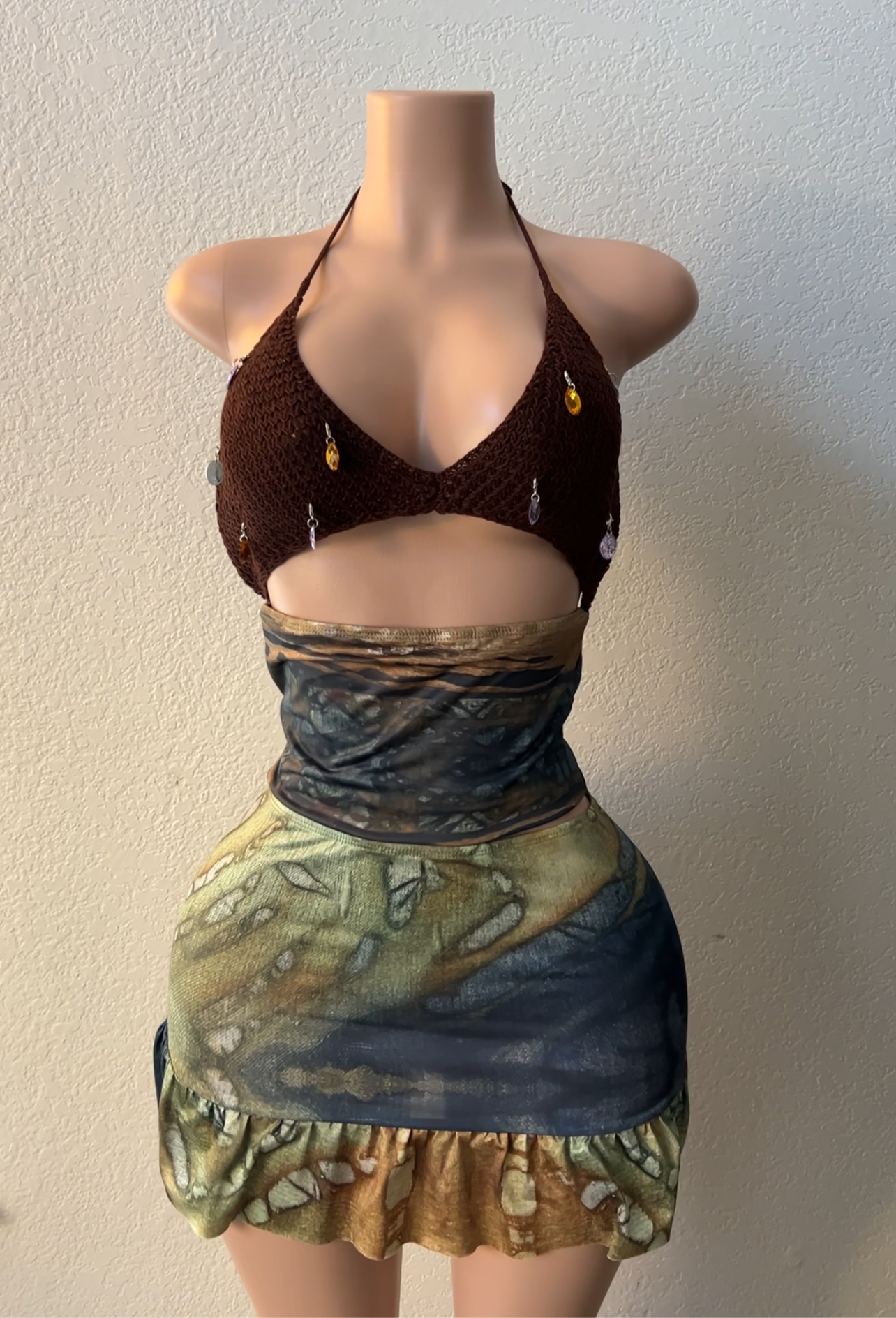 Mannequin wearing a brown top and colorful skirt against a plain background